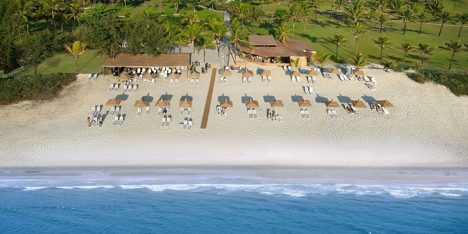 Beachfront resort with loungers, palm trees, and scenic ocean views
